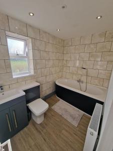 a bathroom with a tub and a toilet and a sink at Stunning Modern Riverside Cottage in Aberdulais