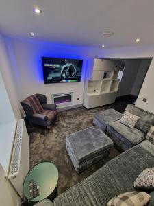 a living room with a couch and a flat screen tv at Stunning Modern Riverside Cottage in Aberdulais