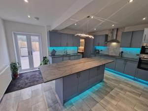 a large kitchen with blue cabinets and a large island at Stunning Modern Riverside Cottage in Aberdulais