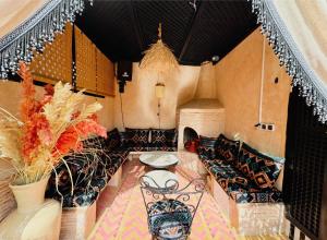 a room with a table and a bench and flowers at Riad Dar Najwa in Marrakesh +31 photos