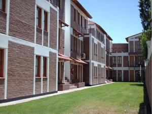 a row of brick buildings with a green lawn at Muras Apart Hotel in Mendoza