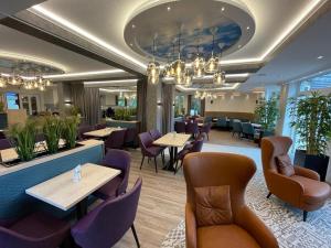 a restaurant with tables and chairs and a chandelier at Hotel Seemeile in Cuxhaven