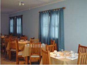 un comedor con mesas y sillas y cortinas azules en Muras Apart Hotel en Mendoza