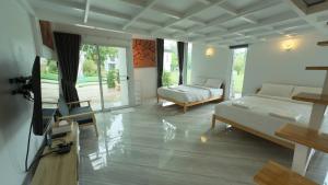 a living room with two beds and a flat screen tv at Milky Way Poolvilla in Ban Wang Takhrai