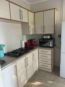 eine Küche mit weißen Schränken und einem Herd mit Backofen in der Unterkunft At 25 Cottage 1 bedroom Balkfontein in Bothaville