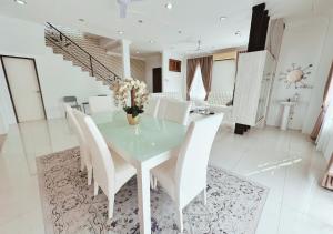 a dining room with a glass table and white chairs at Bangi BungalowStay in Kajang