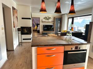 a kitchen with orange and black cabinets and a living room at Wellness Ferienwohnung Szymecki- Sauna & Whirpool bei Heidelberg in Schönau