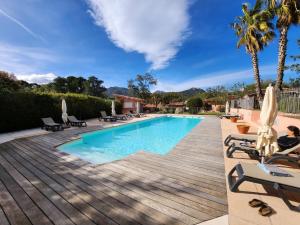 a swimming pool with a wooden deck and chaise lounge chairs at Bavella in Zonza