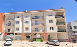 Un gran edificio blanco con coches aparcados delante. en A la Vera de Alarcón, en Motilla del Palancar