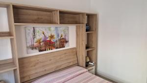 a bedroom with a wooden headboard with a picture above a bed at Casa Alda-A due passi dal centro in Alghero