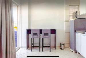 a kitchen with two bar stools in front of a counter at LOFT no Centro de Campos Novos in Campos Novos