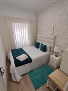 une petite chambre avec un lit blanc avec des oreillers bleus dans l'établissement casa saloia, à Nazaré