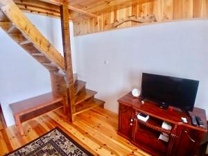 a living room with a television and a staircase at Ethno Cottage Momo Tepca in Žabljak