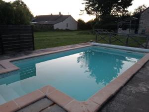 a swimming pool with blue water in a yard at Tiny house sous le chene in Saint-Roch