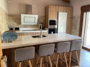 a kitchen with a large counter with four bar stools at Casa Rural 3 Suspiros in Torre de Santa María