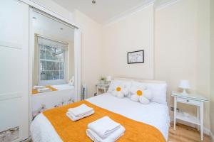 ein weißes Schlafzimmer mit einem Bett mit Handtüchern darauf in der Unterkunft Notting Hill & Hyde Park, Chic 2 DBL bedroom flat, 1 min to Tube & Portobello Rd in London