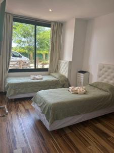 a bedroom with two beds and a large window at Cabaña La Arianna in Santa Teresita