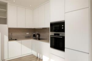 a kitchen with white cabinets and black appliances at Marco 4 Seasons- Winter in Arco da Calheta