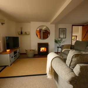 a living room with a couch and a fire place at Mulberry Cottage in Beckford