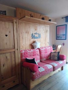 Un sofá sentado en una habitación con una pared de madera. en Les Eglantines studio non adapté aux personnes avec des difficultés physiques, en Bolquere Pyrenees 2000