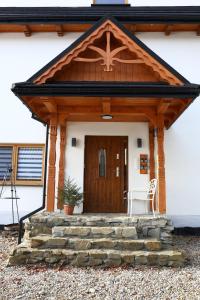 Apartamenty Baj na Polnej - Studio Trzy Horyzonty في PyzÃ³wka: الشرفة الأمامية للمنزل مع باب خشبي