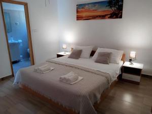 a bedroom with a large bed with two towels on it at Apartmani Goga Tomić in Seline
