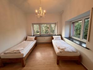 two beds in a room with windows and a chandelier at Bohlen-Mühle - Monteurzimmer Reuhl in Mühltal