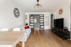 a white living room with a bed and a television at Bel appartement calme à Bois-Colombes in Bois-Colombes