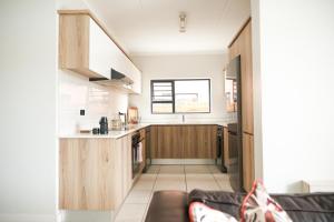 a kitchen with wooden cabinets and a couch in a room at Blyde Beach Front Apartment Ground floor in Pretoria
