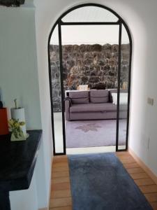 ein Wohnzimmer mit einer Couch durch eine Glastür in der Unterkunft Antico Dammuso Venedisè in Pantelleria