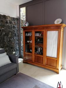 einen Holzschrank in einem Wohnzimmer mit einem Sofa in der Unterkunft Antico Dammuso Venedisè in Pantelleria