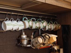 Un mucchio di tazze appese a un appendiabiti in cucina di Lo Specchio dei Papiri a Napoli