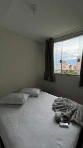 a bedroom with a white bed with a window at Imperial Hotel in Aparecida