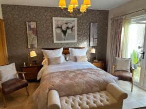 a bedroom with a large bed and two chairs at Crowfield Country House in Aghadowey