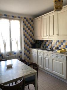 een keuken met witte kasten en een tafel met stoelen bij Proximité Palais des Festivals in Cannes