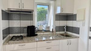 a kitchen with white cabinets and a sink and a window at LOW HEAD beachside bungalow "Cockle Shell" in Low Head