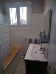 Un baño con lavabo, espejo y ventana. en House, en Blois