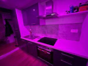una cucina viola con lavandino e bancone di Nuit magique jacuzzi, terrasse & lit motorisé - 008 a Rouen