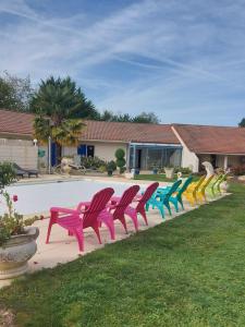 a row of colorful chairs sitting next to a pool at La Galerne in Neuville-de-Poitou