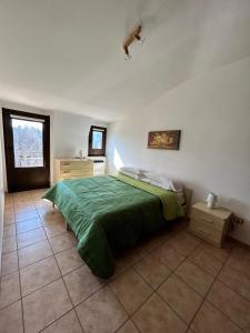 a bedroom with a bed with a green comforter at La Tana di Antea in Lorica