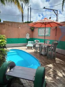 un patio con mesa, sombrilla y piscina en Hospedagem Chapéu Virado, en Belém