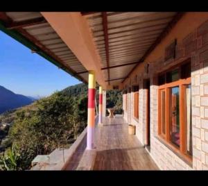 a porch of a building with a view of a mountain at Hariyali Homestay in Chopta