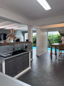 a kitchen with a sink and a dining room with a table at Les pieds dans l'eau, Cilaos in Cilaos