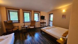 a hotel room with two beds and chairs and windows at Hotel Izvorat Arda - Хотел Изворът Арда in Arda