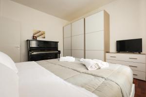 a bedroom with a white bed and a television at Modena Visit Apartment in Modena