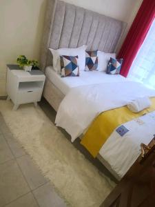 a bedroom with a large bed and a night stand at Charity homes in Ruiru