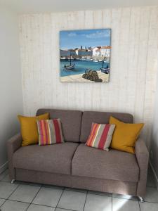 a couch in a room with two paintings on the wall at Le Petit Bois in Sainte-Marie-de-Ré