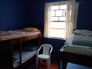 a bedroom with two bunk beds and a white chair at Hostel Baladi in Socorro +3 photos