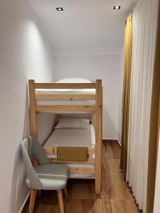 a small bedroom with a bunk bed and a chair at Celestia Apartments in Shkodër