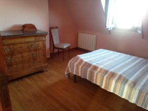 a bedroom with a dresser and a bed and a chair at Maison récente type traditionnelle 9 couchages in Trizac